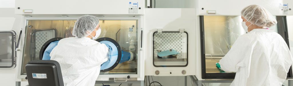 Zwei Mitarbeiter*innen in steriler Schutzkleidung am Isolator